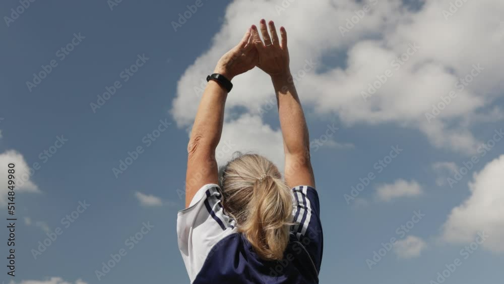active mature senior woman doing sports outdoors in park, exercise to cool down, take deep breath, raise hands up in air. concept of active healthy retirement lifestyle. breathing exercises in fresh active mature senior woman doing sports outdoors in park, exercise to cool down, take deep breath, raise hands up in air. concept of active healthy retirement lifestyle. breathing exercises in fresh