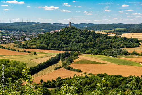 Der Bergfried der H  henburg Vetzberg auf einem Vulkanberg in Mittelhessen  eingebettet in eine landwirtschaftlich genutzte Landschaft mit leicht bew  lktem Himmel am Horizont bei sch  nem Sommerwetter