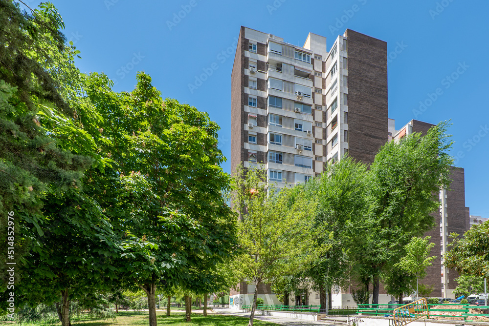 Facade of a residential building of fourteen heights surrounded by grass and trees