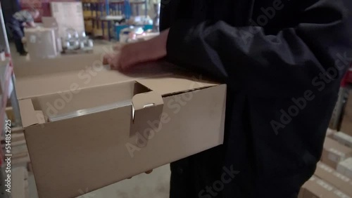 Professional Warehouse Worker Checks and Seales Cardboard Box Ready for Shipment. hd photo