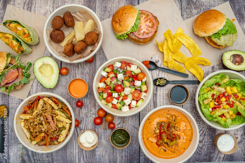 Set of dishes  salads  latin food  hamburgers  avocados and cherry tomatoes on a brown table