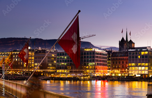 Swiss flag on Mont-Blanc bridge in Geneva during evening.