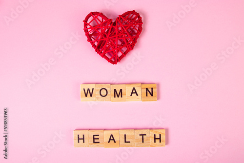 Wooden lettering and red heart on pink background. Womens health.