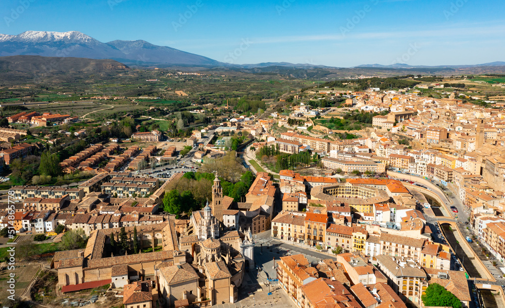 Picturesque aerial view of Tarazona cityscape on banks of Queiles river overlooking ancient cathedral and bullring with snow-capped Moncayo mountain range in background in spring, Spain