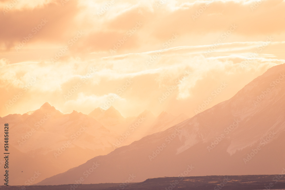Fototapeta premium silueta de montañas con nubes anaranjadas del atardecer brillante, hora dorada en montañas 