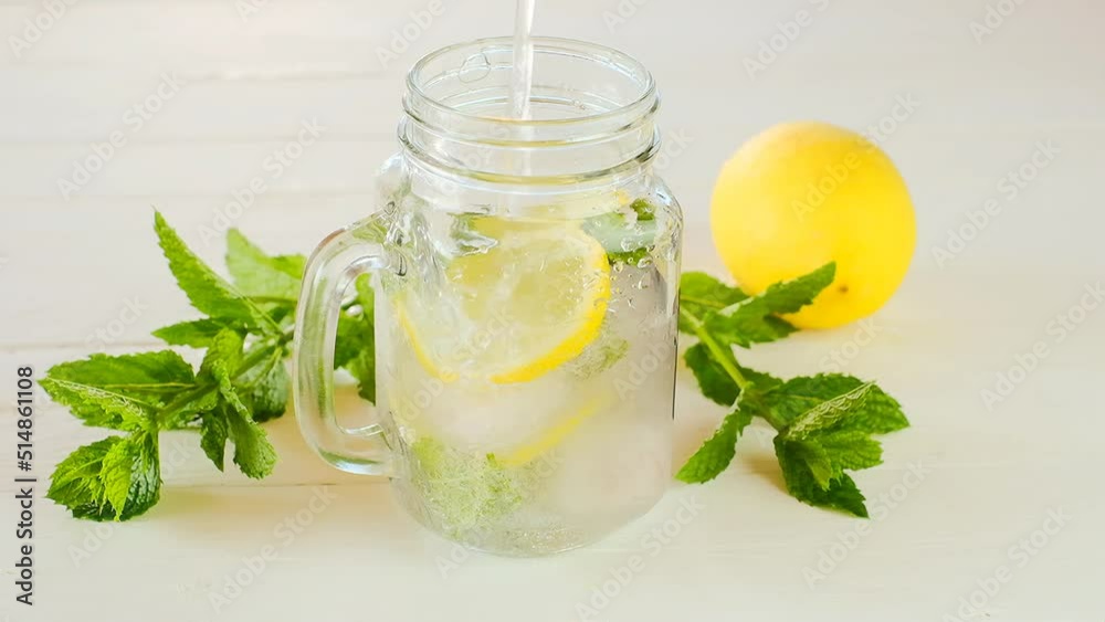 Lemon mint water with ice in a transparent mug.Citrus cocktail with mint leaves. Sassy lemon water.Dietary lemon drink. piece of ice falls into a glass with a cocktail. Lemon summer drink. Lemon mint water with ice in a transparent mug.Citrus cocktail with mint leaves. Sassy lemon water.Dietary lemon drink. piece of ice falls into a glass with a cocktail. Lemon summer drink.
