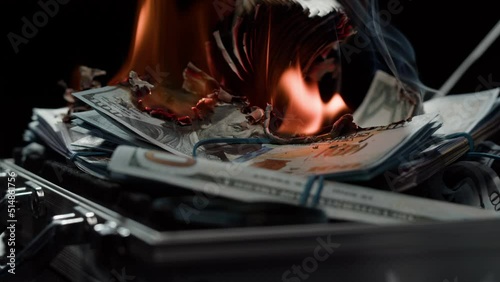 Burning American hundred dollar banknotes, Flame of fire from money. Rich person having stacks of 100 US dollars in metallic suitcase. Paper money loss, financial crisis and depressed economy.  photo