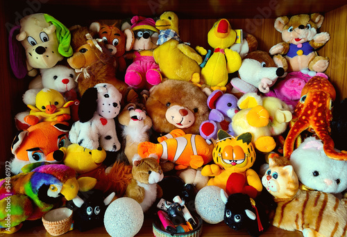 collection of colorful stuffed animals and teddies stacked in a closet covering the background surface © Domingo