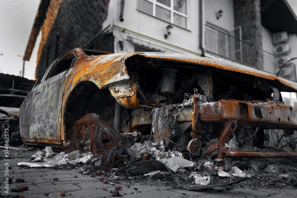 Fototapeta premium A burnt-out destroyed car near a civilian building. The result of mortar shelling during the Russian-Ukrainian war.