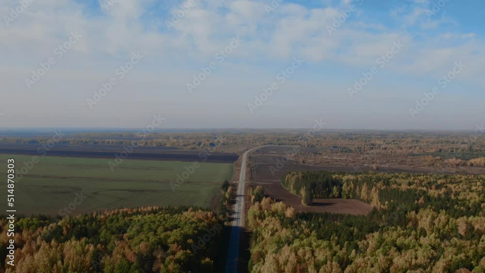 Road between yellow and green autumn forest and fields in Ural, Russia. Beautiful autumn nature landscape at during daytime. Aerial view from a drone Road between yellow and green autumn forest and fields in Ural, Russia. Beautiful autumn nature landscape at during daytime. Aerial view from a drone