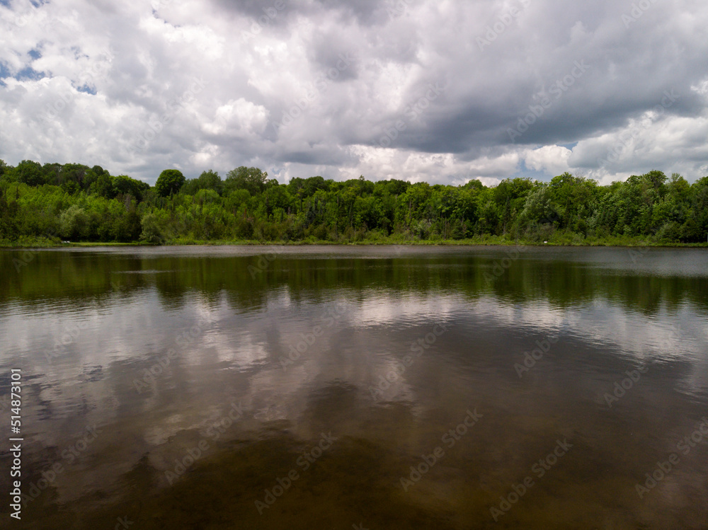 Large clouds are reflected in a small lake in cottage county in Ontario, Canada.