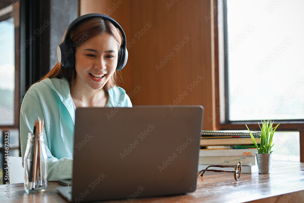 Charming young asian female college student studying an online lesson via her laptop Charming young asian female college student studying an online lesson via her laptop