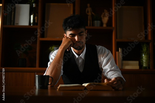 Thoughtful asian businessman focused reading some paragraph on the book