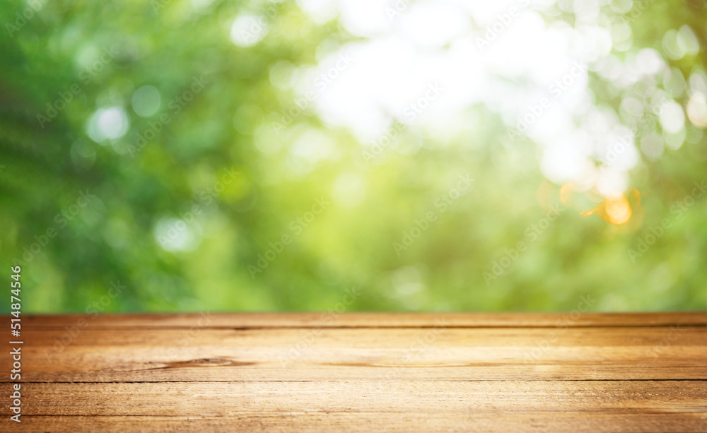 Empty rustic wooden texture of old wood table top, blur against green park with defocused sunlight, blurred foliage backyard background. Display mock up, montage your product, design key visual layout Empty rustic wooden texture of old wood table top, blur against green park with defocused sunlight, blurred foliage backyard background. Display mock up, montage your product, design key visual layout