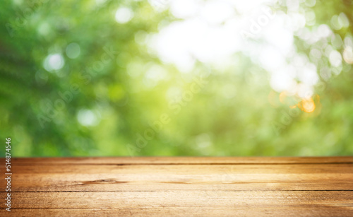 Empty rustic wooden texture of old wood table top, blur against green park with defocused sunlight, blurred foliage backyard background. Display mock up, montage your product, design key visual layout