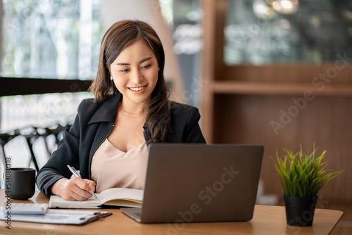 Asian businesswoman working using laptop computer in modern office Make an account analysis report with financial graphs and real estate investment data. financial and tax system concepts