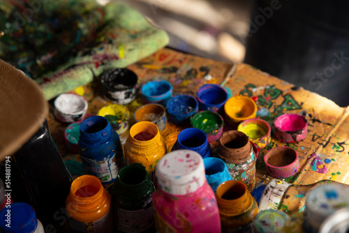 Several small jars of colored paints on outdoor table