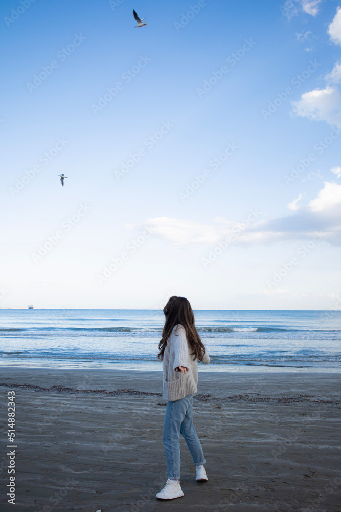 Young woman from behind is turning around at the beach near the sea in Cyprus