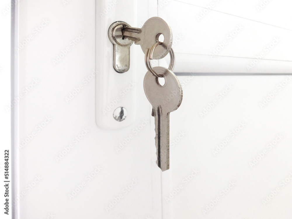 Two keys hanging on a white alluminim door