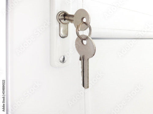 Two keys hanging on a white alluminim door