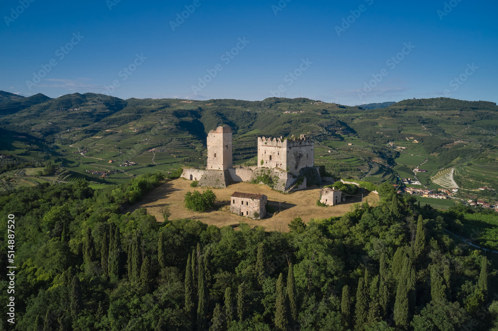 Medieval castle on a hill aerial view. An ancient castle in Italy surrounded by vineyards is a point of interest. Scaliger Castle of d'Illasi in the province of Verona, built in the 10th century.