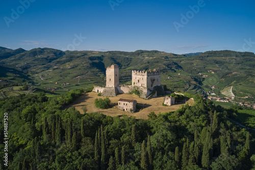 Medieval castle on a hill aerial view. An ancient castle in Italy surrounded by vineyards is a point of interest. Scaliger Castle of d Illasi in the province of Verona  built in the 10th century.