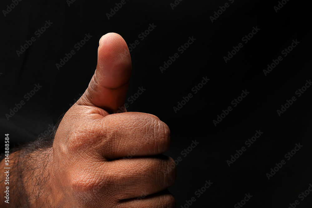 Asian male dark skinned single hand fist finger on black background thumbs up finger sign