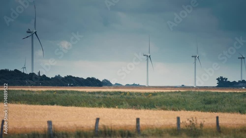 A row of wind turbines in the wheat fields. Slow-motion, pan follow photo