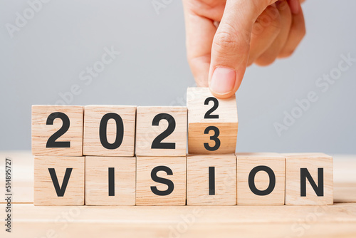hand flipping block 2022 to 2023 VISION text on table. Resolution, strategy, goal, motivation, reboot, business and New Year holiday concepts