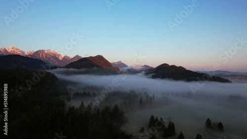 Aerial video of a foggy sunset in the mountain landscape near the stunning Neuschwanstein castle in Hohenschwangau, Germany.  photo