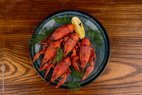 large boiled crayfish in a plate on a wooden background top view