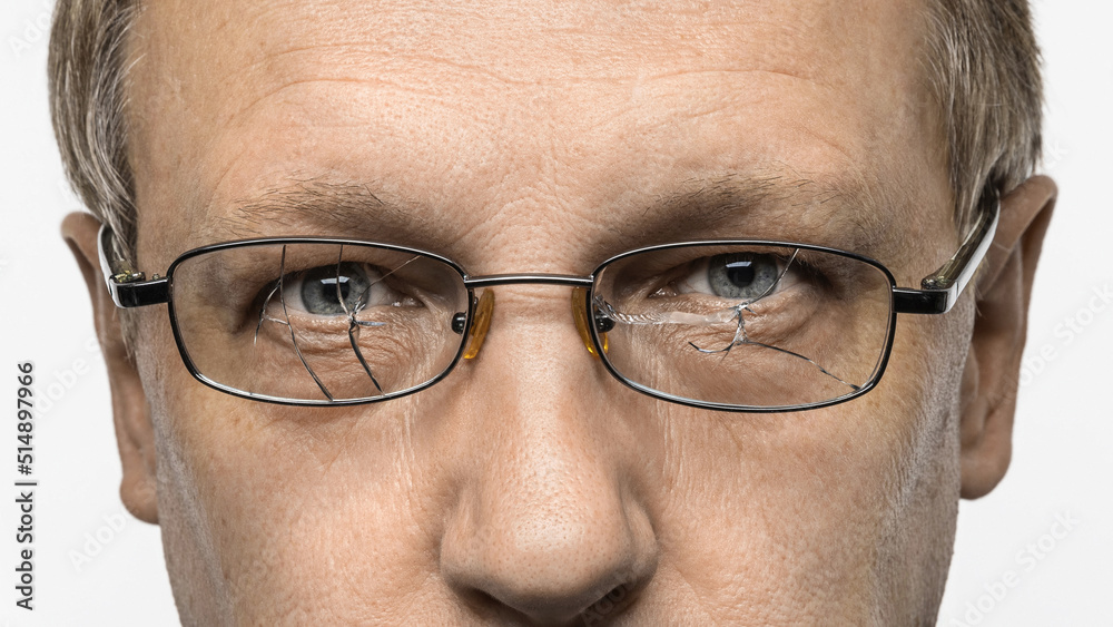 A middle-aged man with broken glasses. Intense look, wrinkles around the eyes. Close-up macro photography. A middle-aged man with broken glasses. Intense look, wrinkles around the eyes. Close-up macro photography.