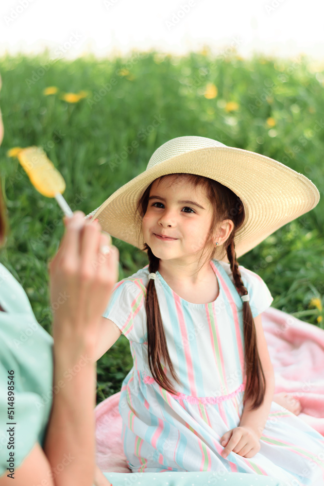 Cute little girl in a straw hat on a picnic with her mom.Summer,family concept.Selective focus,close-up.