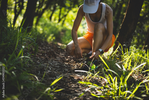 Photography Woman runner tying shoelace on forest trail