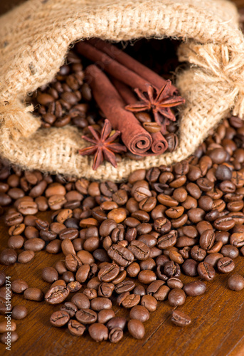 Coffee beans, two cinnamon sticks and anise stars are scattered on a wooden table. copyspace. © Irina Ukrainets