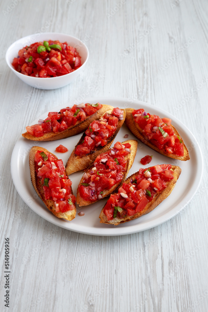 Homemade Italian Tomato Bruschetta with Basil on a Plate, side view. Homemade Italian Tomato Bruschetta with Basil on a Plate, side view.