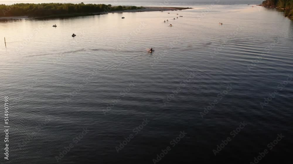 Aerial drone view of group of people kayaking in the river at sunset. Tourists in boats doing water sport during summer holidays on sea. Paddling kayakers in evening. Healthy lifestyle. Active travel 