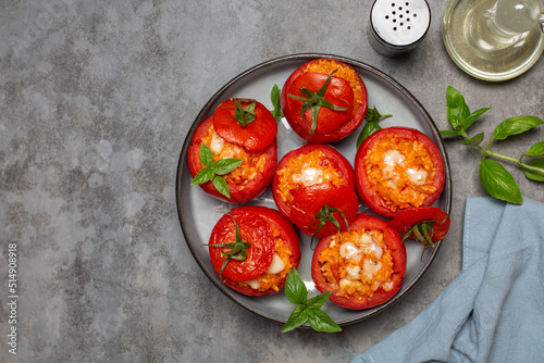 Baked stuffed tomatoes with rice and cheese. Top view. Grey table, copy space. photo