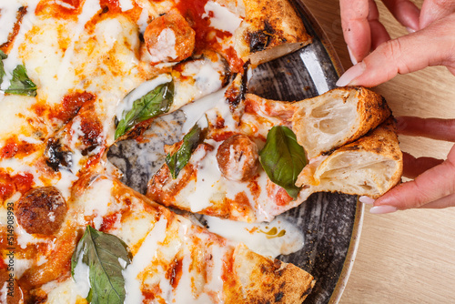 Pizza Napoletana Gourmet con polpette di carne, basilico fresco, parmigiana di melanzane e crema di formaggio tra le mani di una cliente