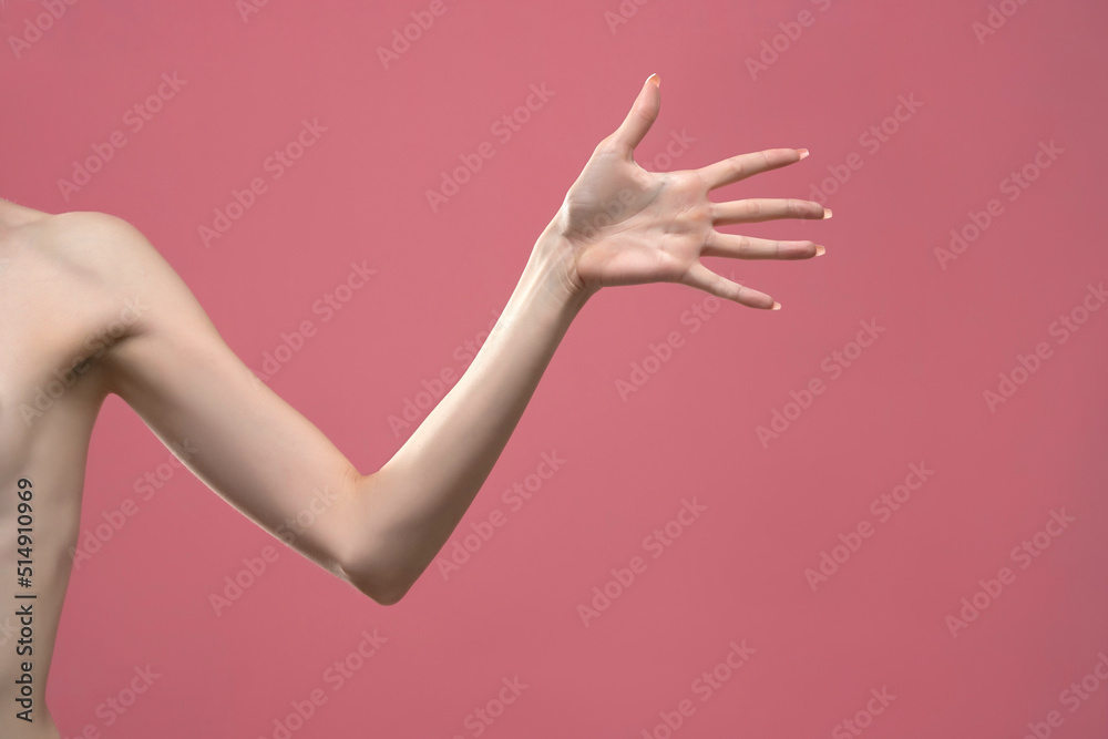 Young woman's stretched arm and palm. Isolated on pink background