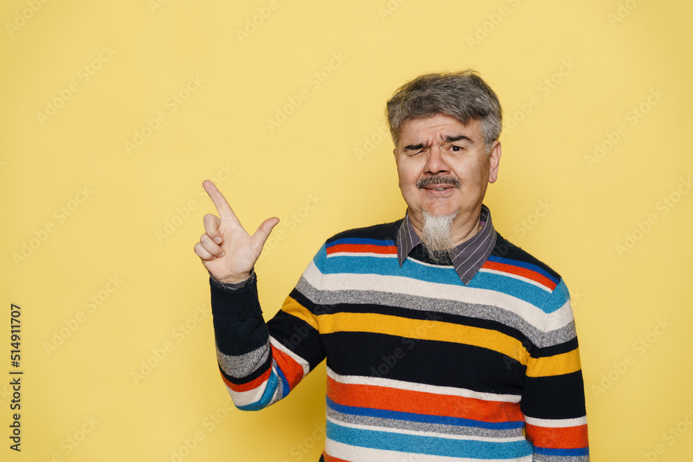 Mature man with grey beard winking and pointing finger aside Mature man with grey beard winking and pointing finger aside