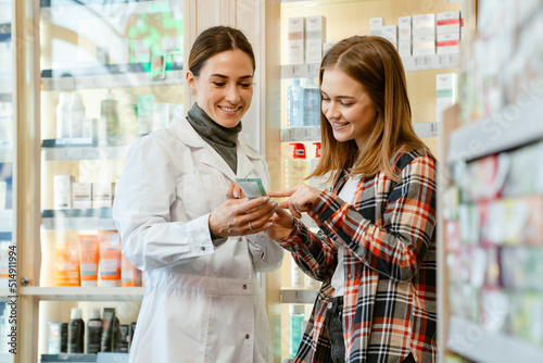 White apothecary wearing lab coat working with customer in pharmacy photo