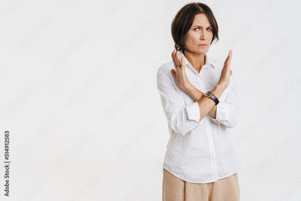 Mature brunette woman frowning while making stop gesture Mature brunette woman frowning while making stop gesture