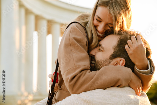 White romantic couple smiling and hugging while walking in park photo