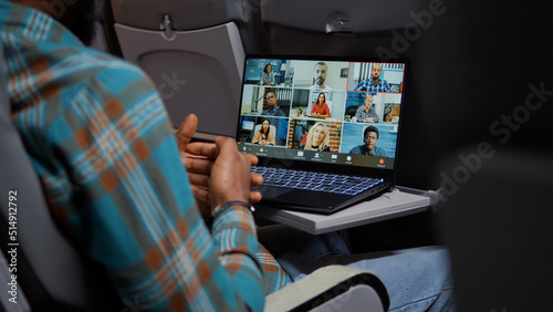 Entrepreneur in airplane attending online videocall meeting with people on remote teleconference chat. Internet telecommunication with videoconference call and webcam. Close up. photo
