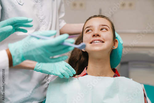 White girl sitting in medical chair while dentists fixing her teeth