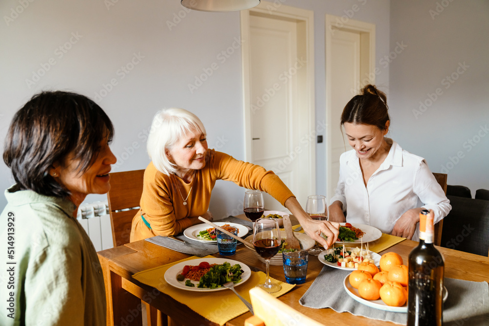 Mature three women smiling and talking while having lunch together