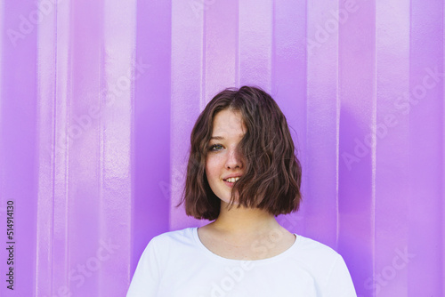 Smiling teenage girl with brown hair in front of purple cargo container