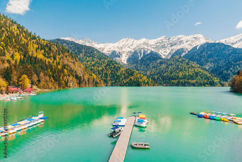 Boats moored by jetty at Lake Ritsa on sunny day photo