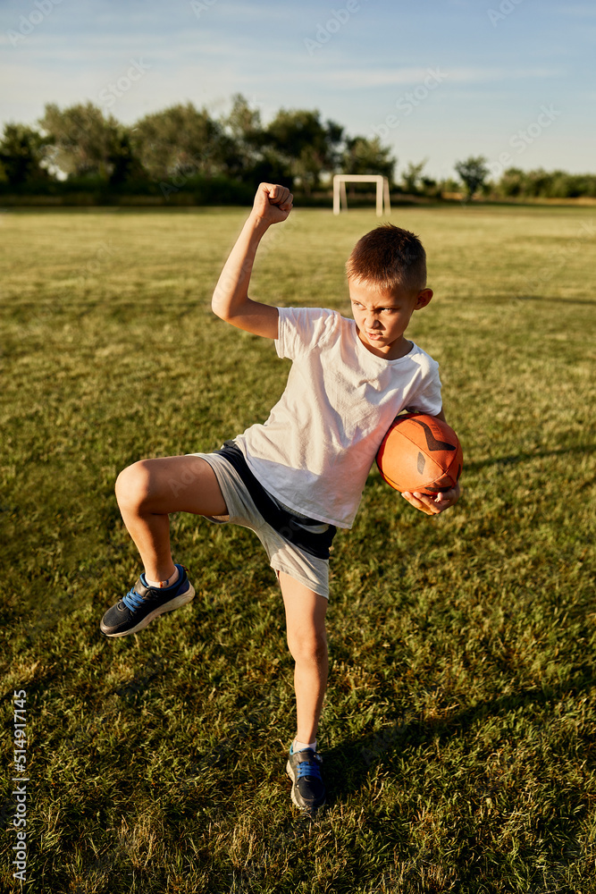 Boy with rugby ball doing haka dance standing on one leg at sports ...